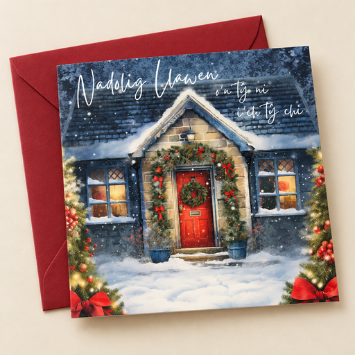 Cerdyn Nadolig O’n Tŷ Ni i’ch Tŷ Chi / Welsh Christmas card with a snowy cottage with a red door, lying flat beside a deep red envelope.