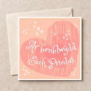 Cerdyn Ar Benblwydd Eich Priodas gyda chalonnau pinc, yn wastad gydag amlen ifori / Welsh anniversary card shown flat with an ivory envelope.